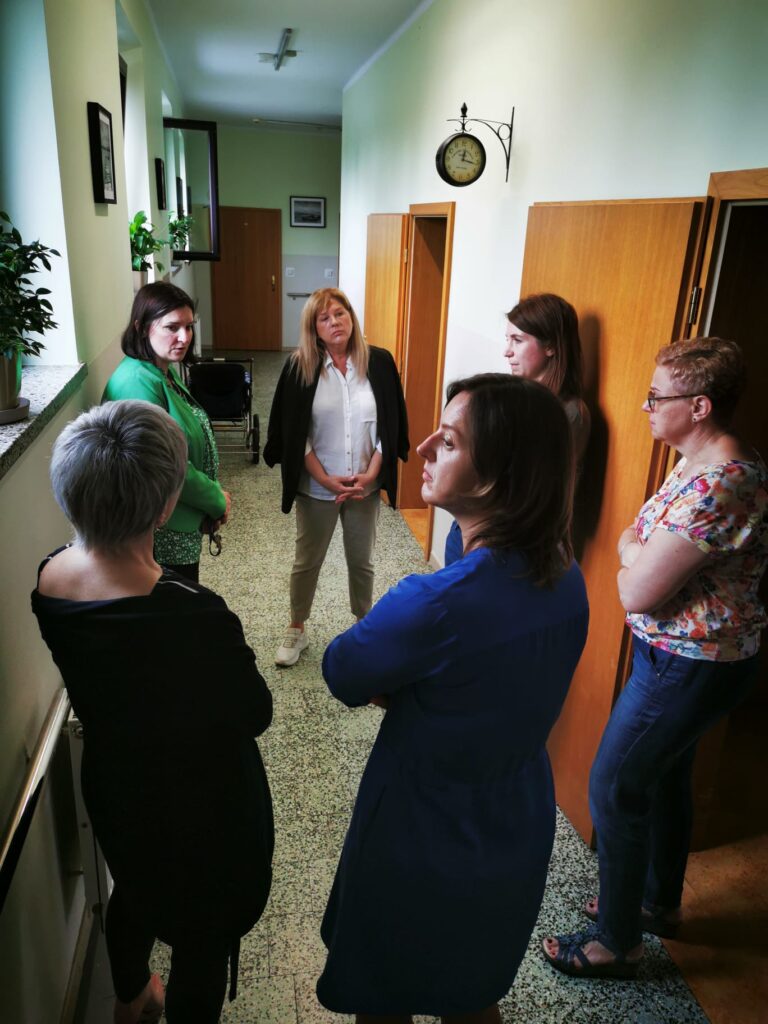 Grupa kobiet stoi w kręgu na korytarzu i rozmawia