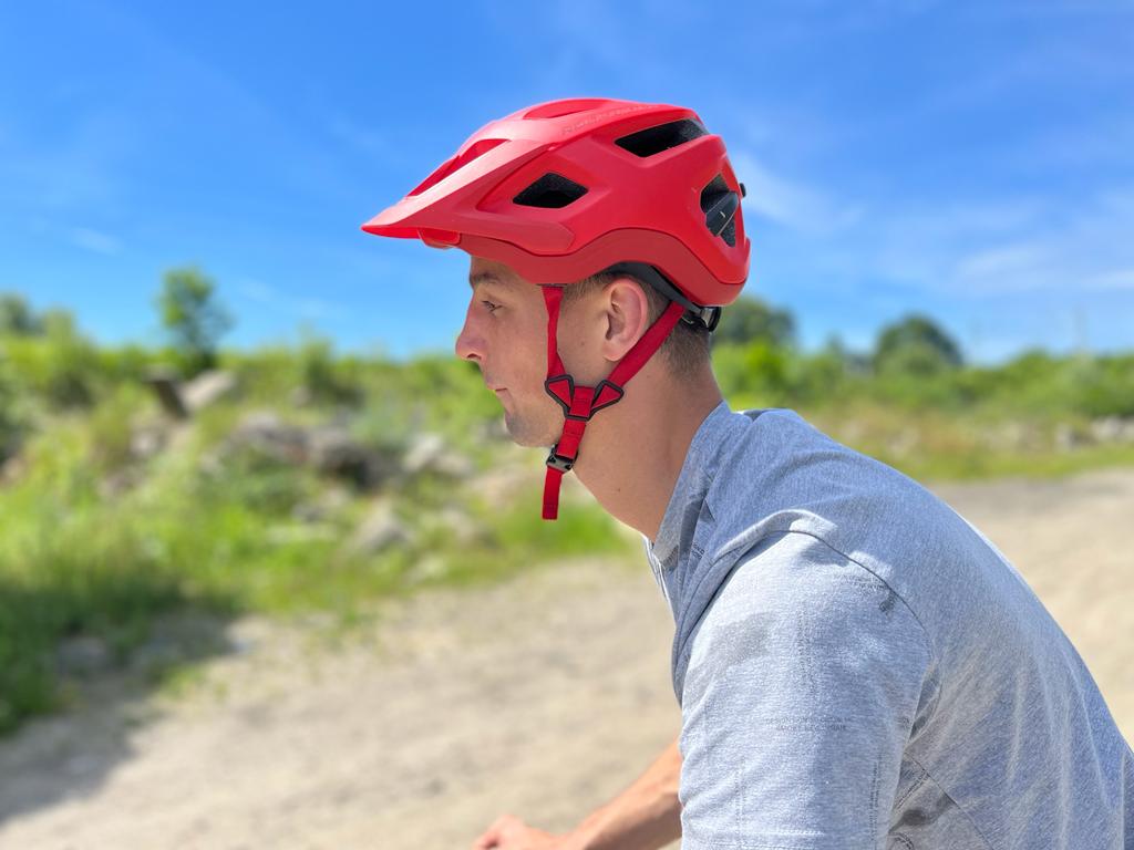 mężczyzna w czerwonym kasku jedzie na rowerze.