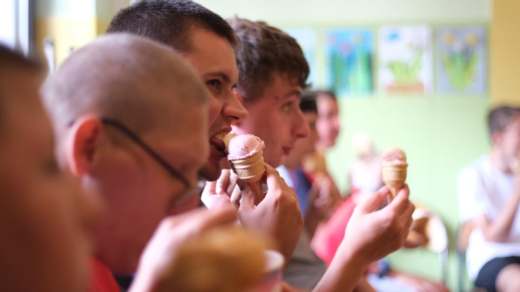 Grupa chłopaków jedząca lody. 