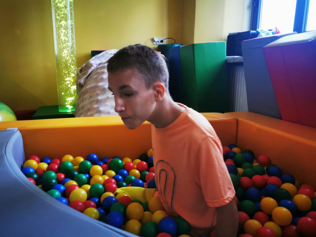 chłopiec w basenie wypełnionym kolorowymi piłeczkami. 