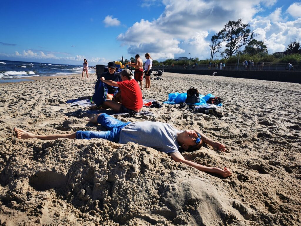 Grupa osób leżąca na plaży 