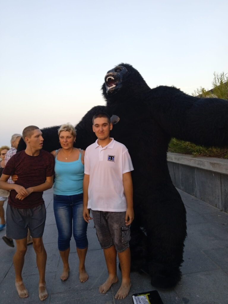 Kobieta i dwoje chłopców pozujących z osobą w przebraniu goryla 