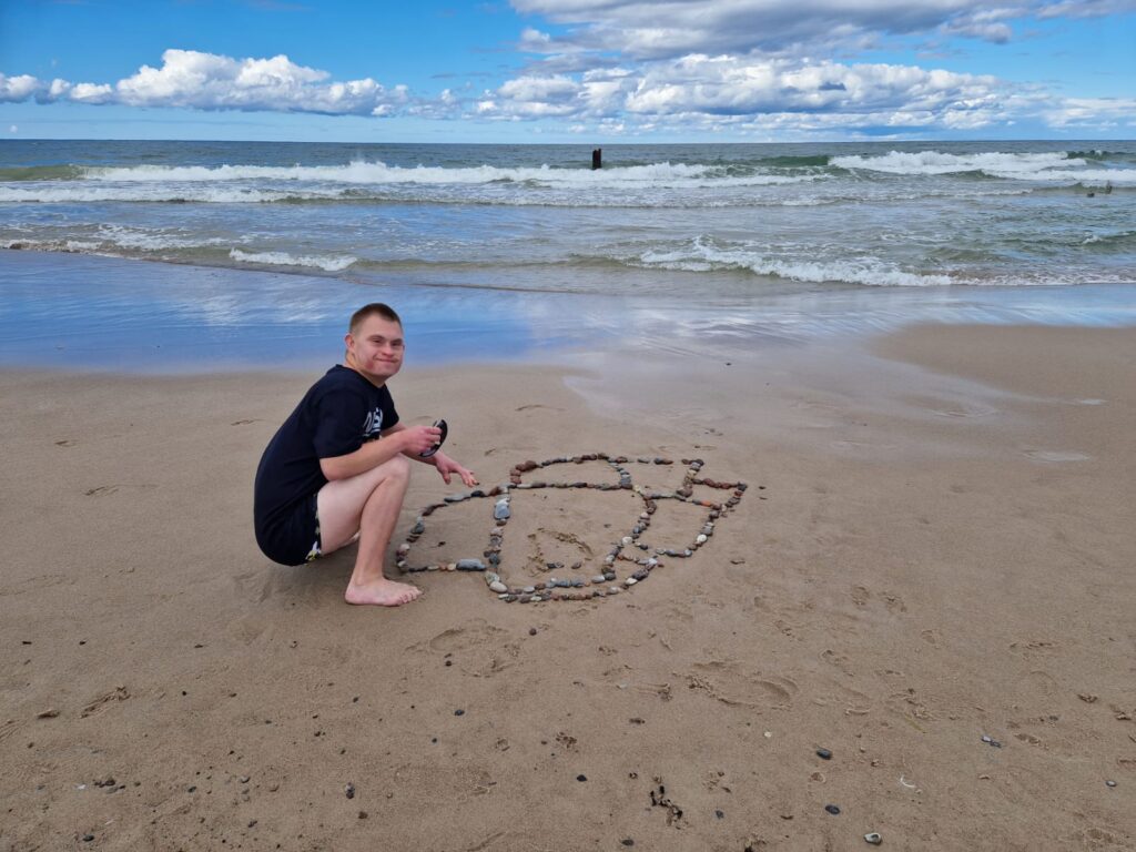 chłopiec na plaży układający obrazek z kamieni 