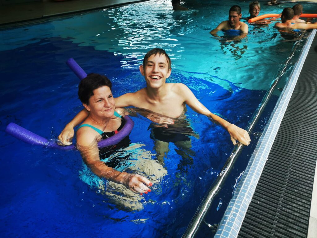 Uśmiechnięci kobieta i chłopiec pływający w basenie.