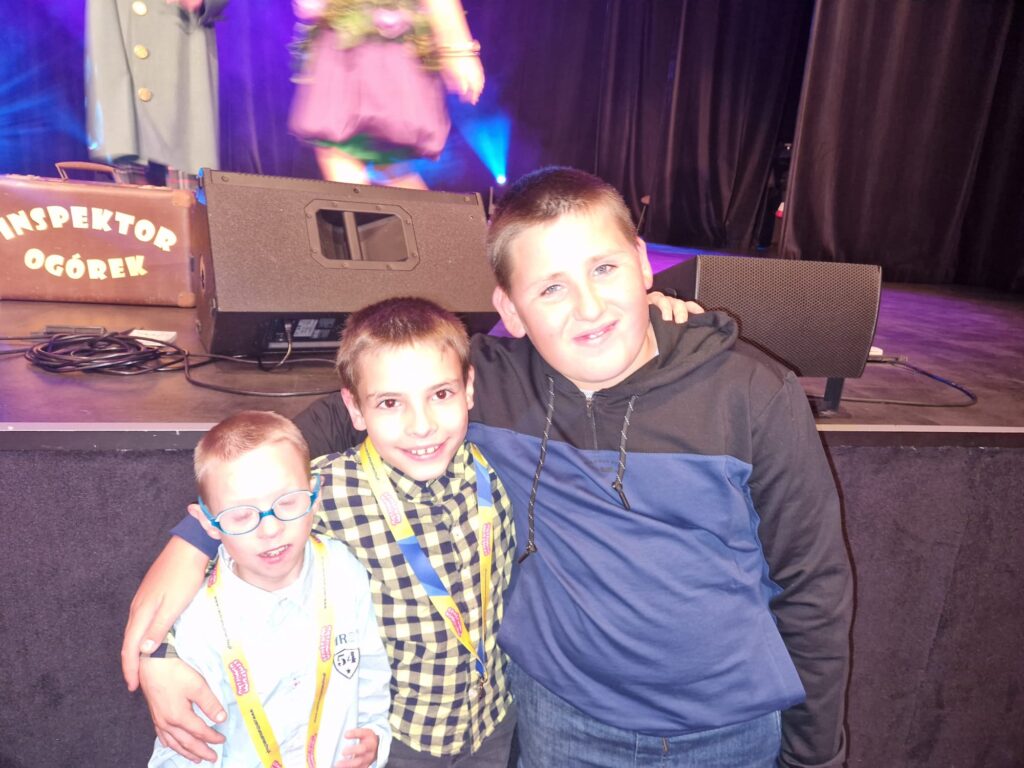 trzech chłopców stojących pod sceną 