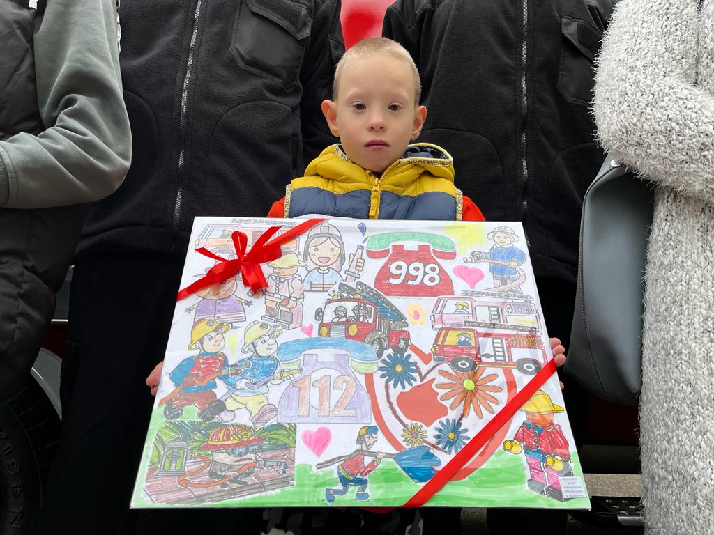 chłopiec trzymający duży obrazek o tematyce strażackiej 