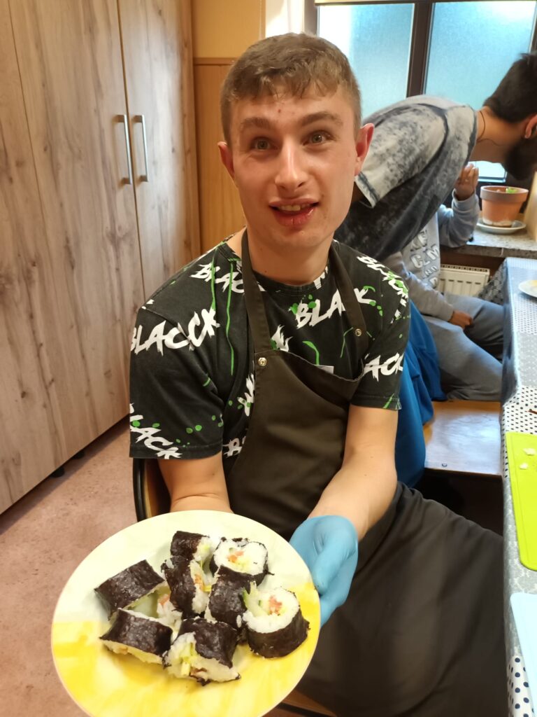 chłopak prezentujący talerz z kawałkami sushi 