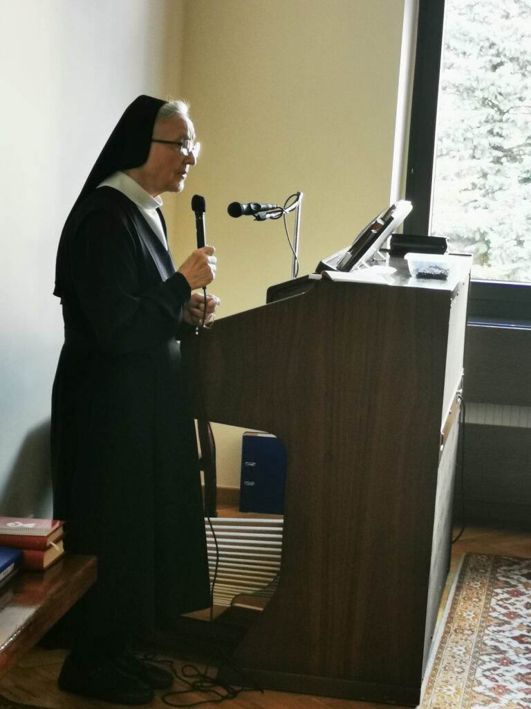 Siostra zakonna stoi za organami. W ręku trzyma mikrofon 