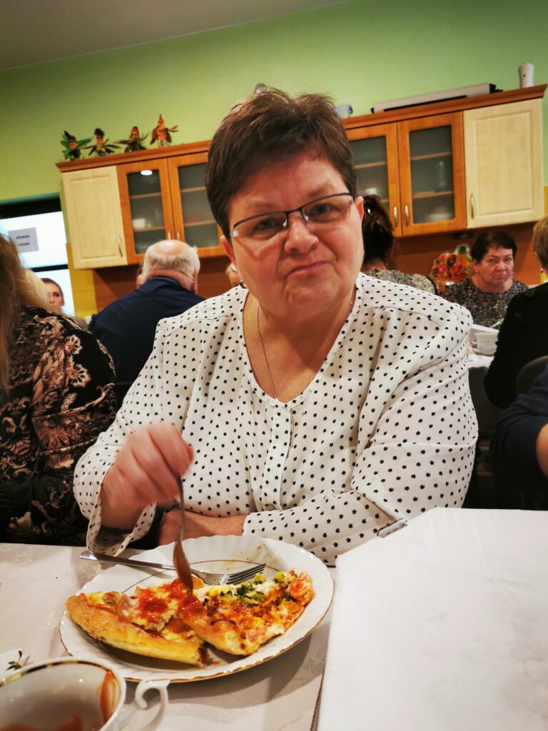 kobieta siedząca przy stole je pizzę. 