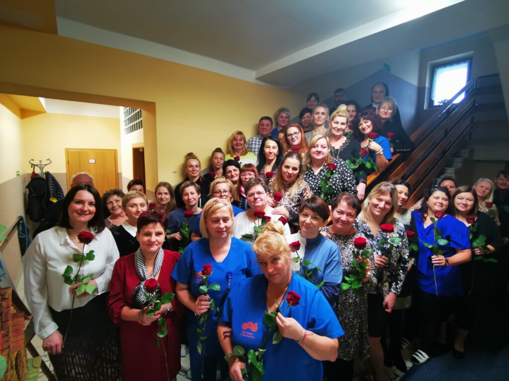 Zdjęcie grupowe na schodach - około 40 osób pozuje z różami w ręku 