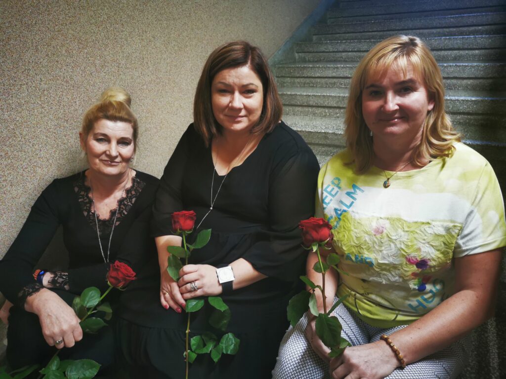 trzy kobiety trzymające róże siedzą na schodach 