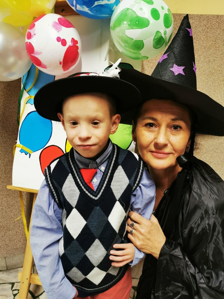 Kobieta w czapce czarownicy pozuje z chłopcem w kapeluszu góralskim 