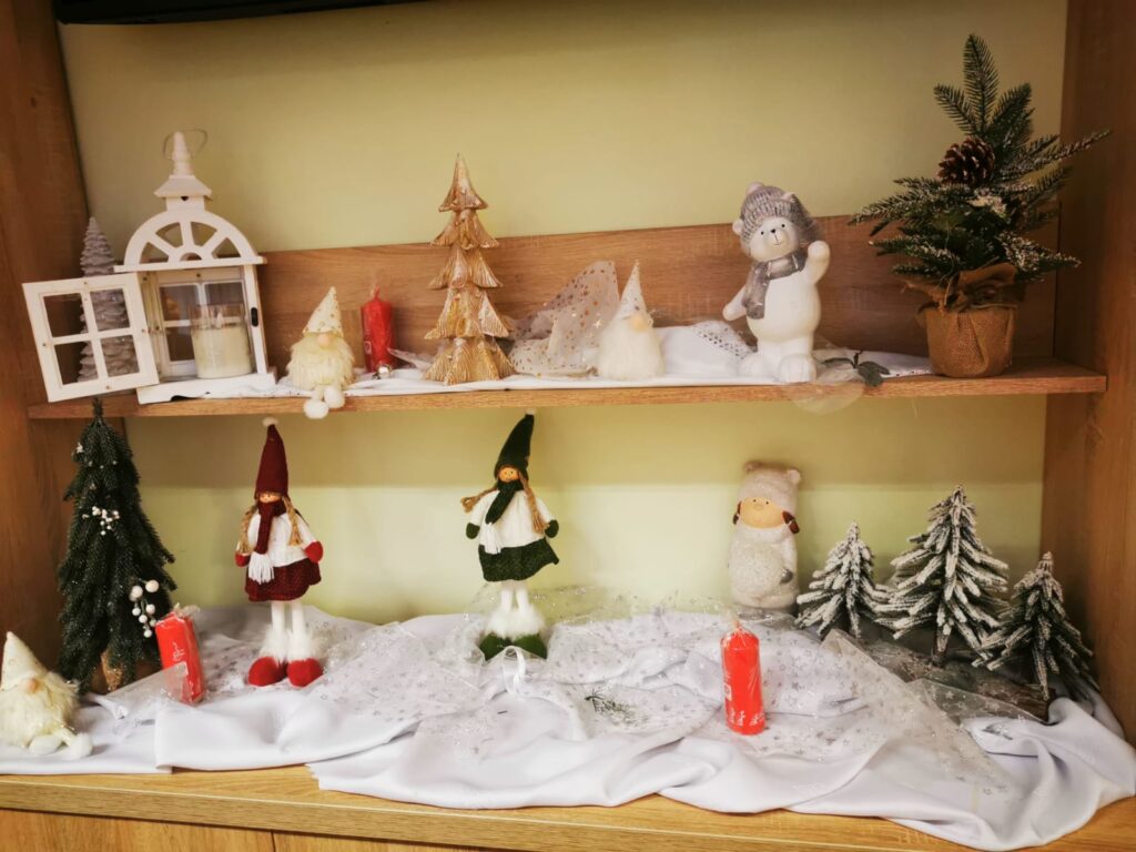Świąteczna dekoracja: na dwóch półkach ustawione różnego rodzaju figurki np. skrzaty, choinki 