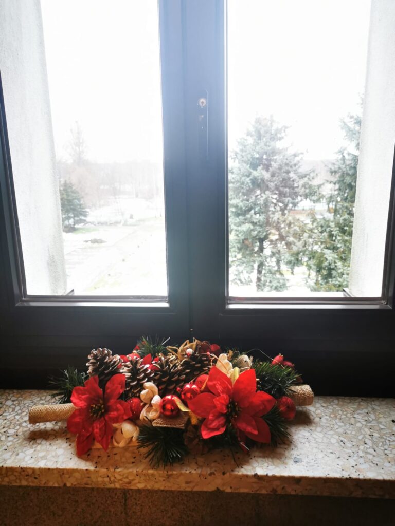 Świąteczna dekoracja: strok i kwiatów, bombek, szyszek i gałązek ustawiony na parapecie. 
