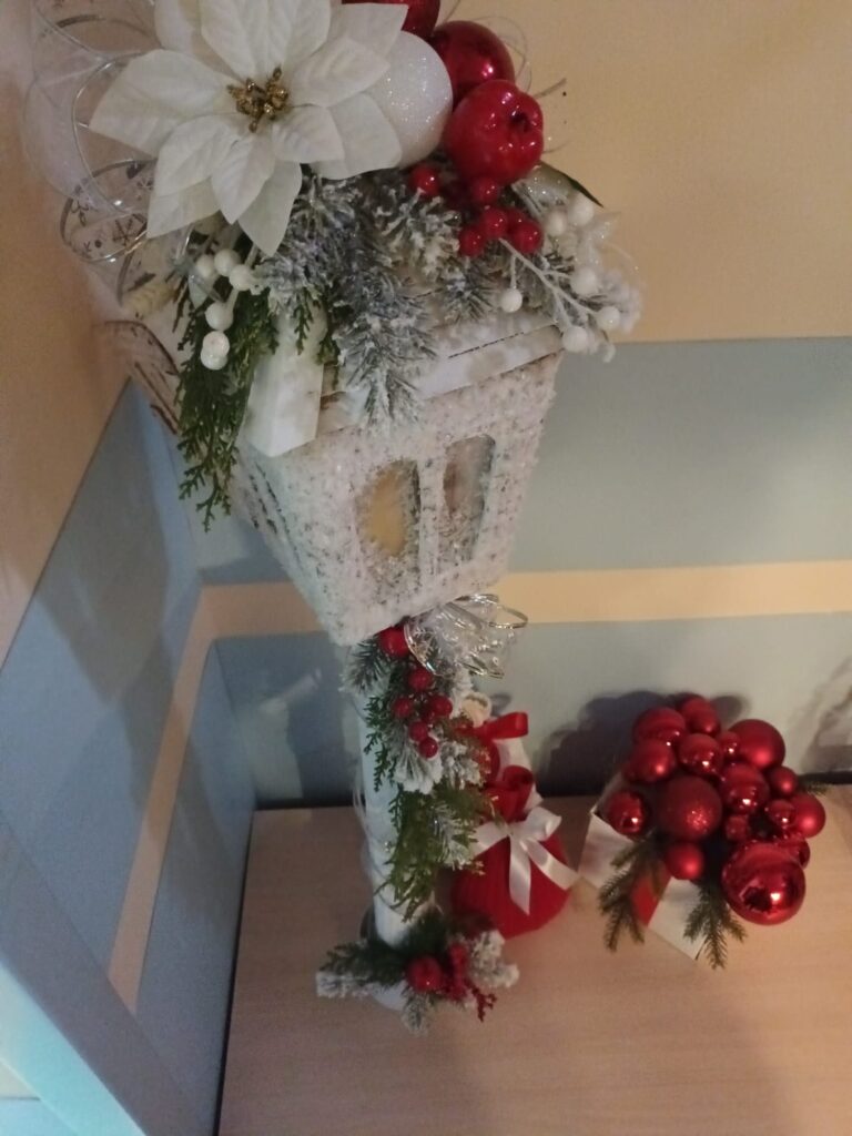 Świąteczna dekoracja: Ręcznie zrobiona latarnia udekorowana kwiatami, gałązkami i bombkami. 