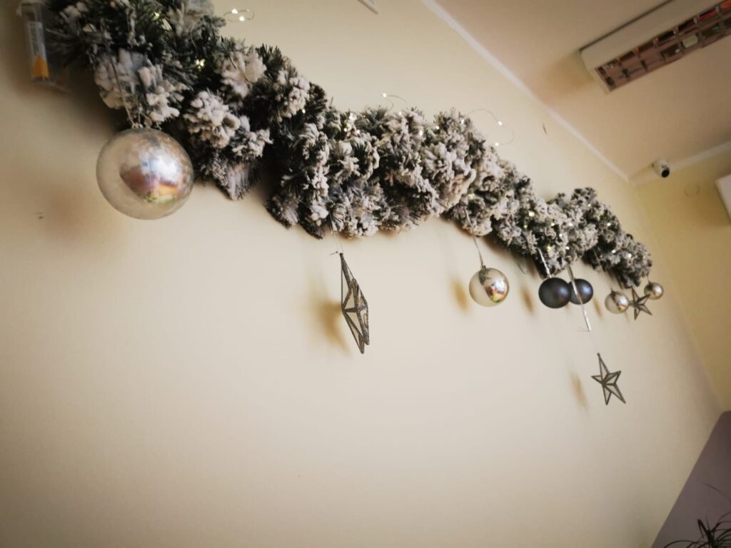 Świąteczna dekoracja: Girlanda z ozdobami świątecznymi zawieszona na ścianie.