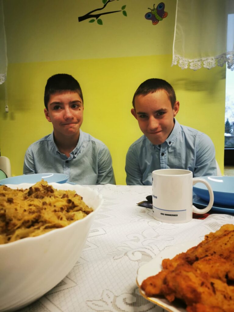 Dwóch chłopców siedzących za stołem. 