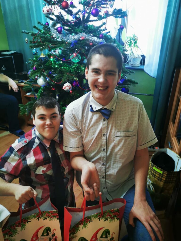 Dwóch chłopaków z prezentami pod choinką. 