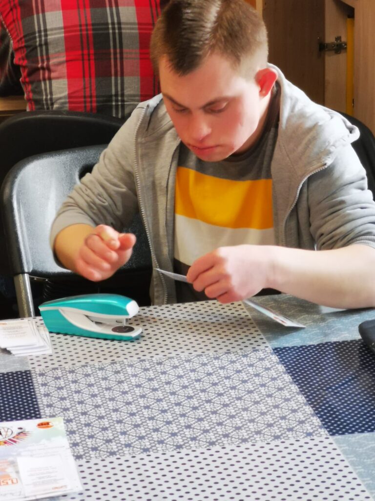 Chłopak zszywający ze sobą dwie kartki 