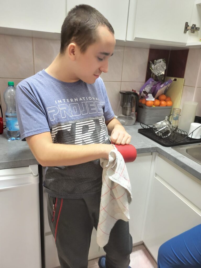 Młodzieniec stojący w kuchni o wycierający kubek. 
