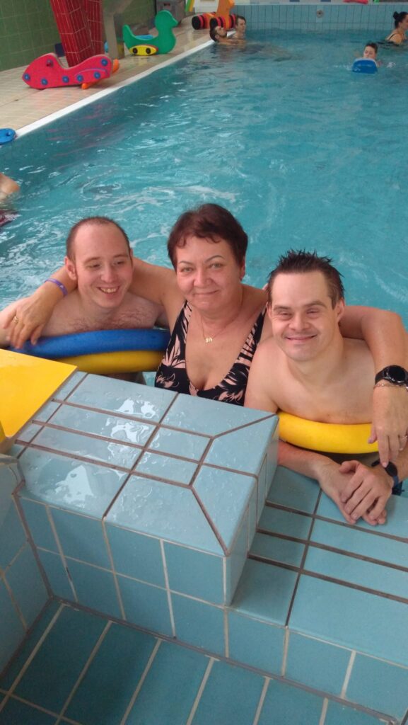 Kobieta i dwóch chłopaków pozują do zdjęcia przy krawędzi basenu. 