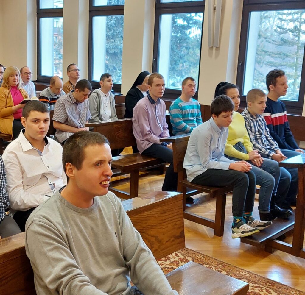 Grupa osób siedząca w kaplicy. 