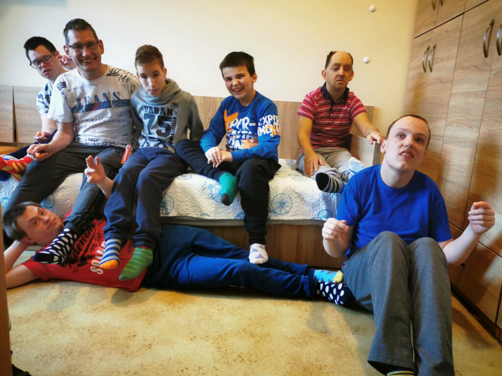 Grupa chłopaków siedzących na łóżkuw kolorowych skarpetach.