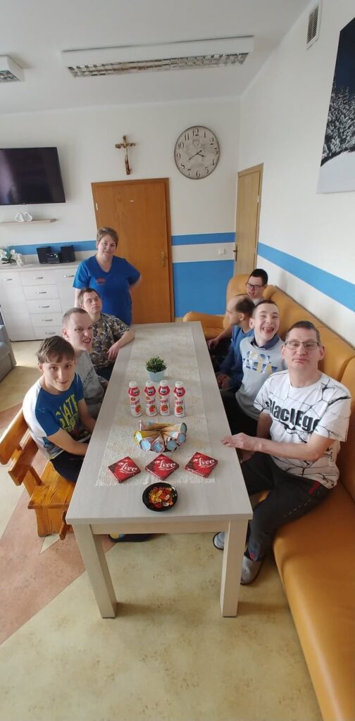 Grupa chłopaków wokół stołu, na którym są ułożone słodycze, jogurty i lody. 