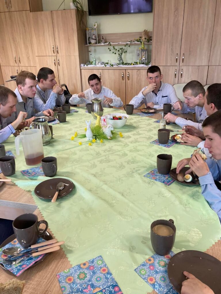Grupa osób wokół stołu jedząca śniadanie. 