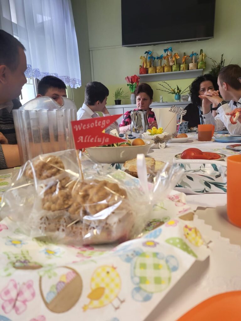 Grupa osób wokół stołu jedząca śniadanie. 