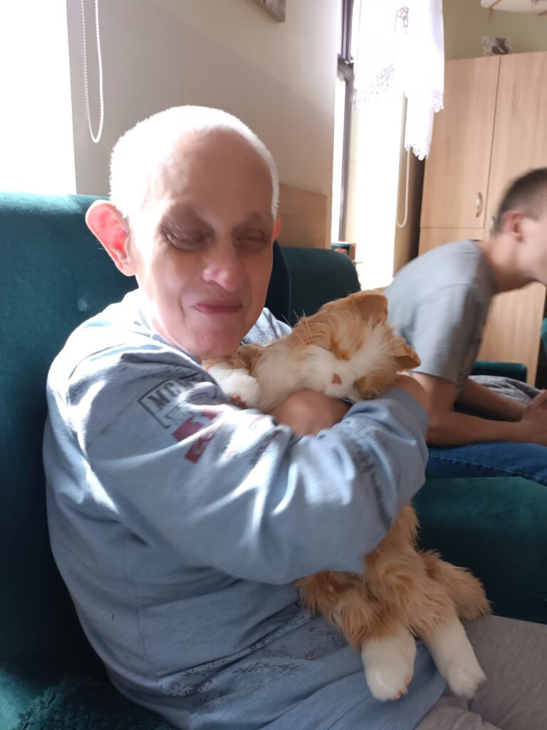 starszy mężczyzna przytula kota. 