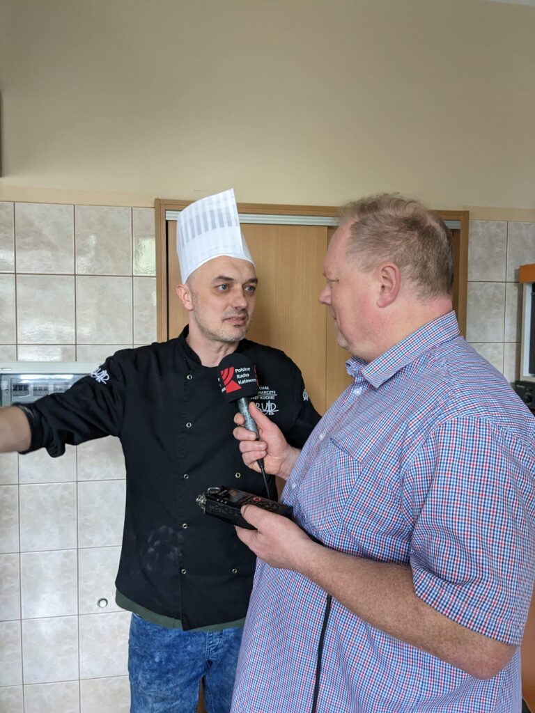 Mężczyzna w ubraniu kucharza udziela wywiadu dziennikarzowi, który trzyma mikrofon z logo radia Katowice. 