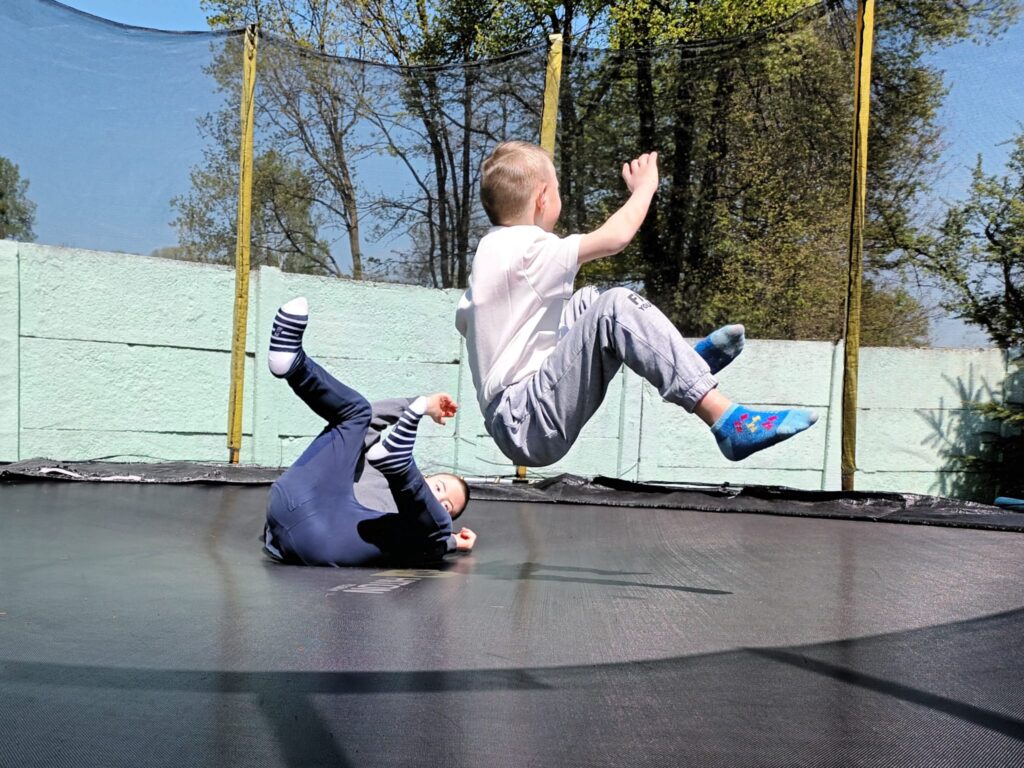Dwaj chłopcy bawiący się na trampolinie. 