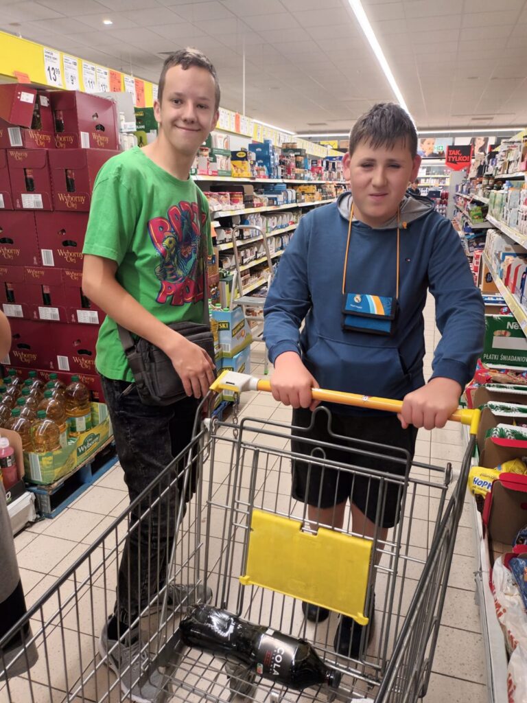 dwoje chłopaków z wózkiem podczas zakupów w markecie 