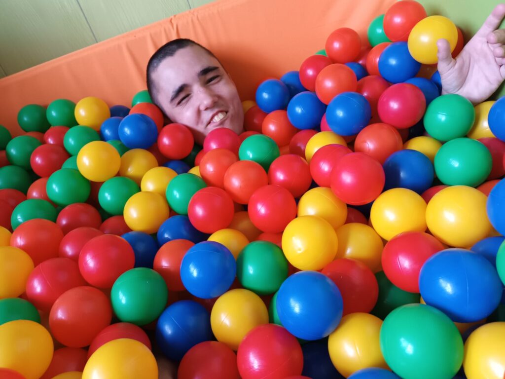 uśmiechnięty chłopak w basenie z kolorowymi kulkami 