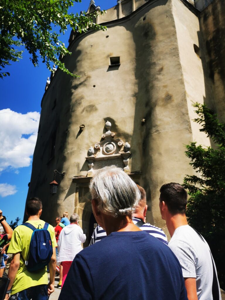 Grupa osób przed wejściem do zamku. 