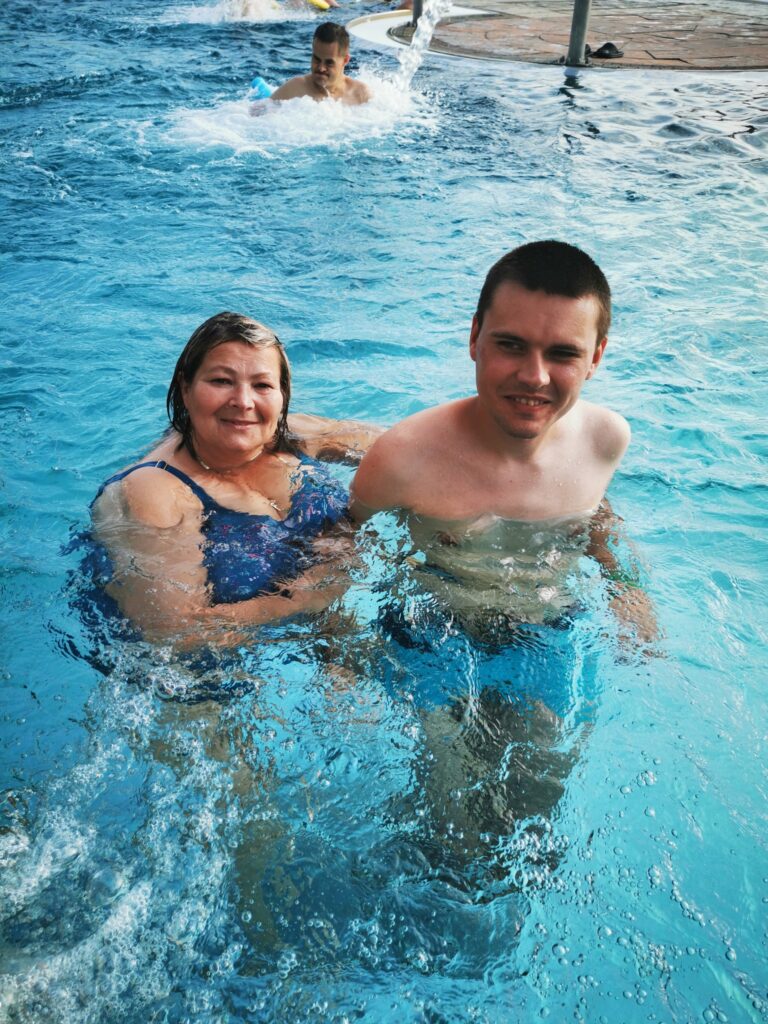 Kobieta i uśmiechnięty chłopak stoją w basenie. 