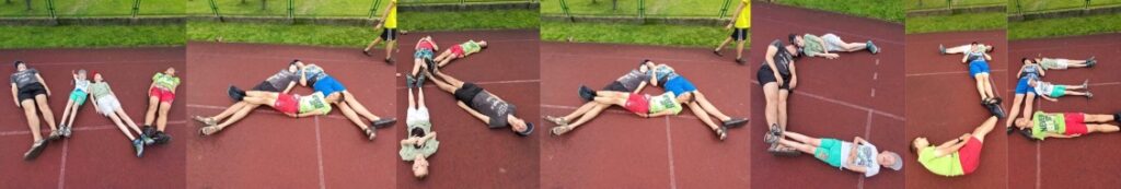 Zdjęcie stworzone z połączenia 7 zdjęć. Na każdym z nich trzech lub 4 chłopaków leży na boisku w taki sposób, by ich ciała układały się w literkę. Wszystkie litery tworzą napis "wakacje" 