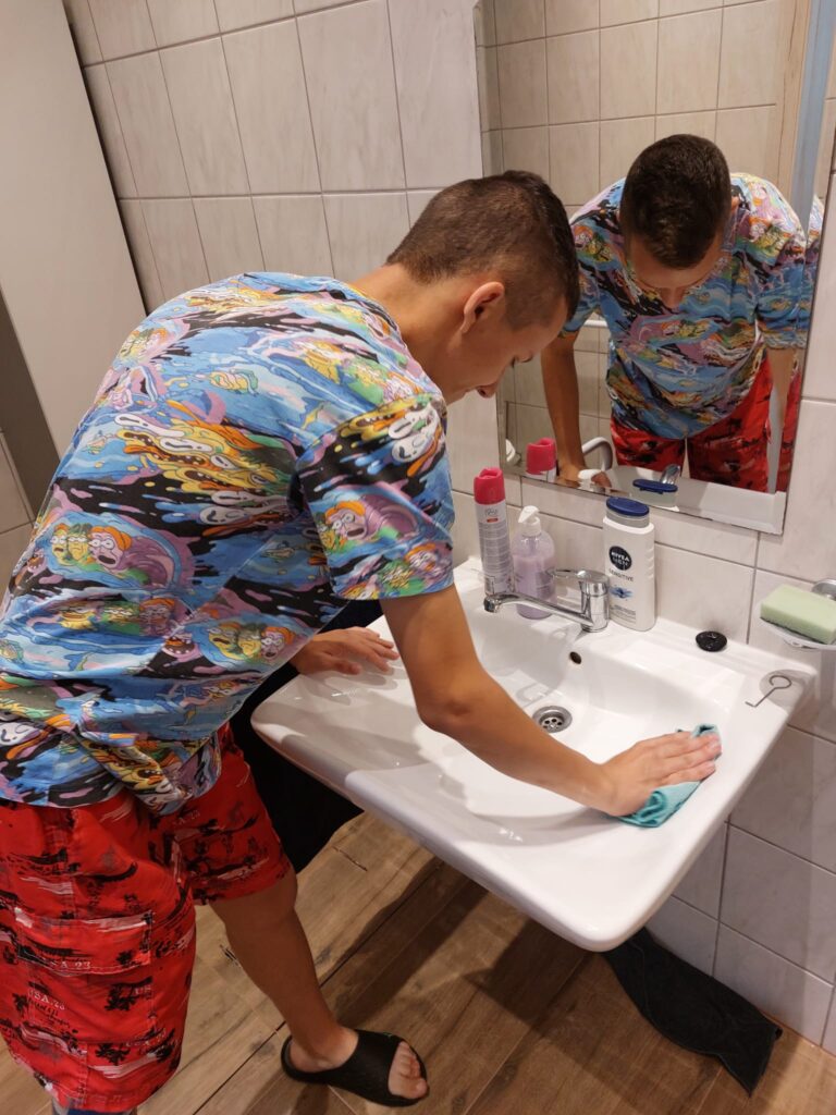 Chłopak myjący umywalkę 