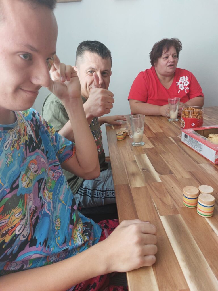 Chłopcy i kobieta przy stole. Piją kawę i rozmawiają. 