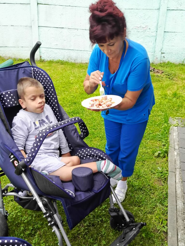 Kobieta karmiąca chłopca siedzącego w wózku 