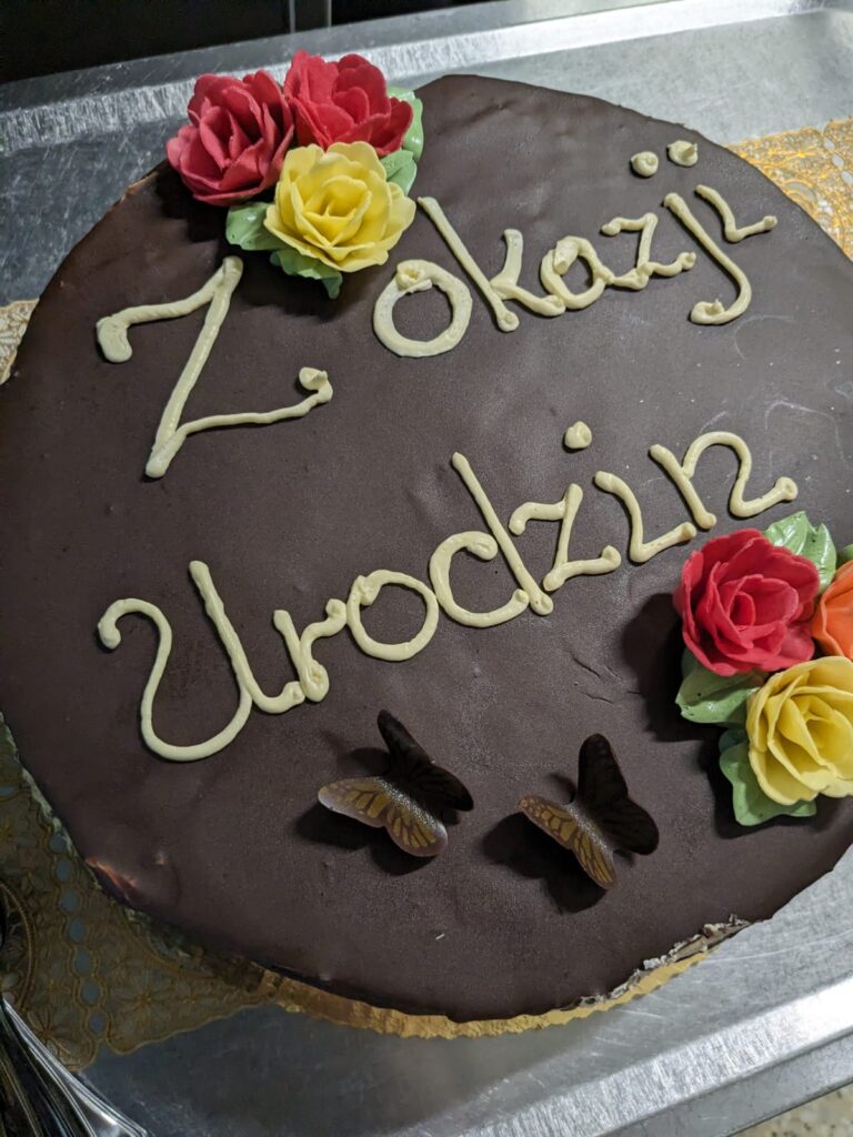 tort z kwiatowymi ozdobami i napisem "z okazji urodzin" 