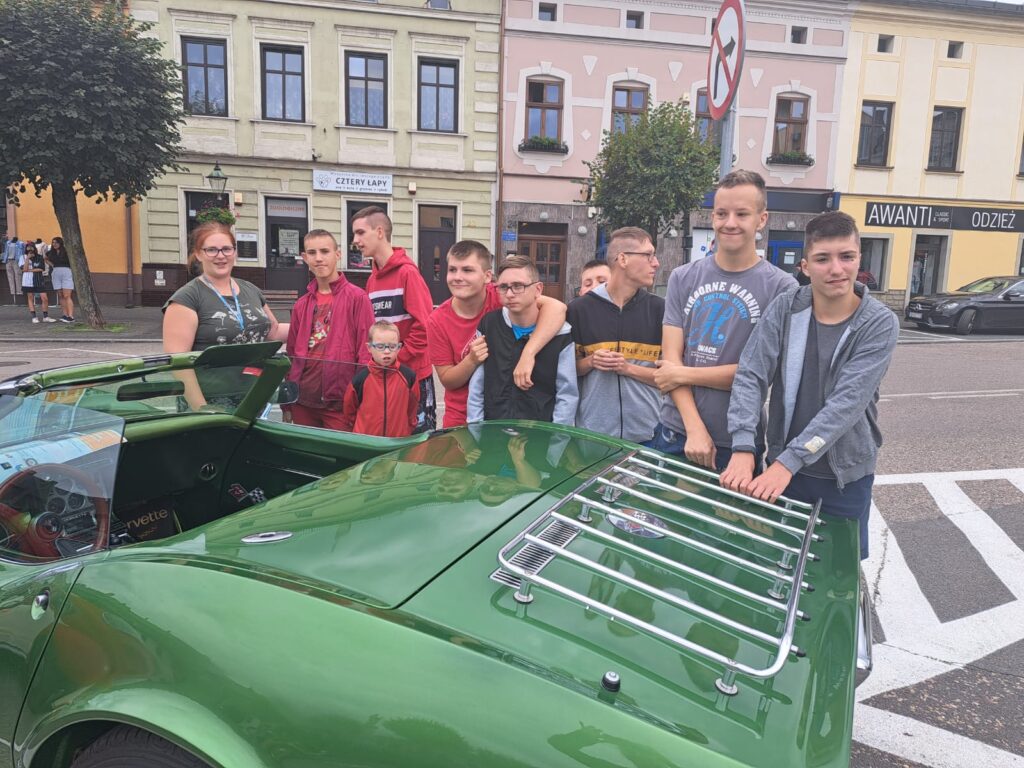Chłopcy wokół zielonego zabytkowego samochodu 