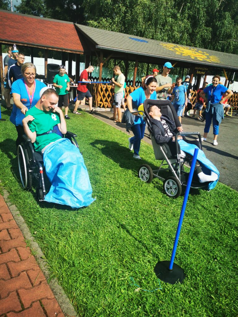 Dwie kobiety biegną pchając przed sobą wózki z niepełnosprawnymi chłopakami. 