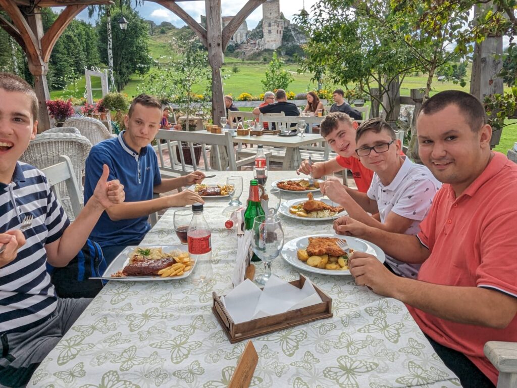 Grupa osób przy stole. Na talerzach pięknie wyglądające dania obiadowe 
