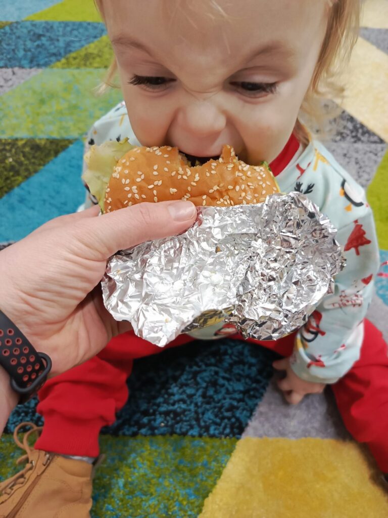 Mały chłopiec jedzący burgera. 
