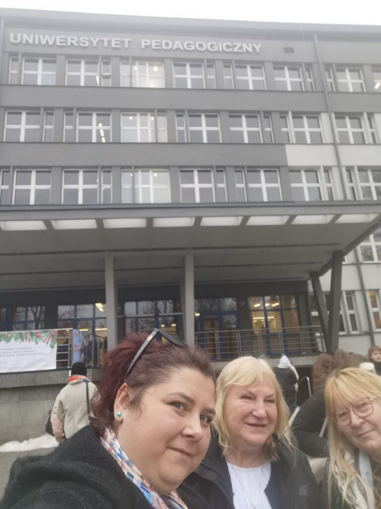 Zdjęcie typu selfie trzech kobiet przed budynkiem z napisem Uniwersytet Pedagogiczny. 