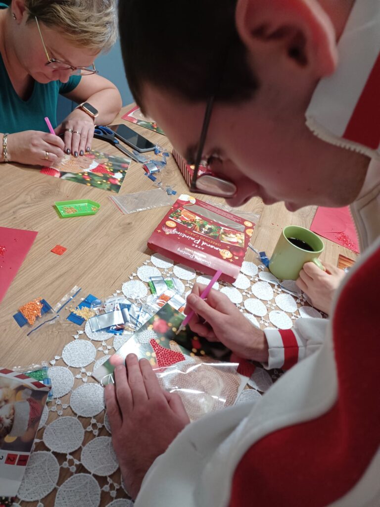 chłopaki przy stole podczas zajęć plastycznych - wykonanie kartek świątecznych z elementami haftu diamentowego. 