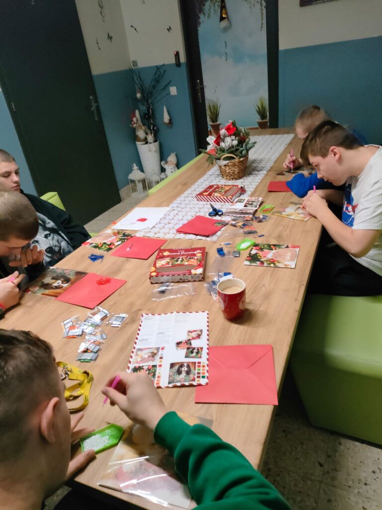 chłopaki przy stole podczas zajęć plastycznych - wykonanie kartek świątecznych z elementami haftu diamentowego. 