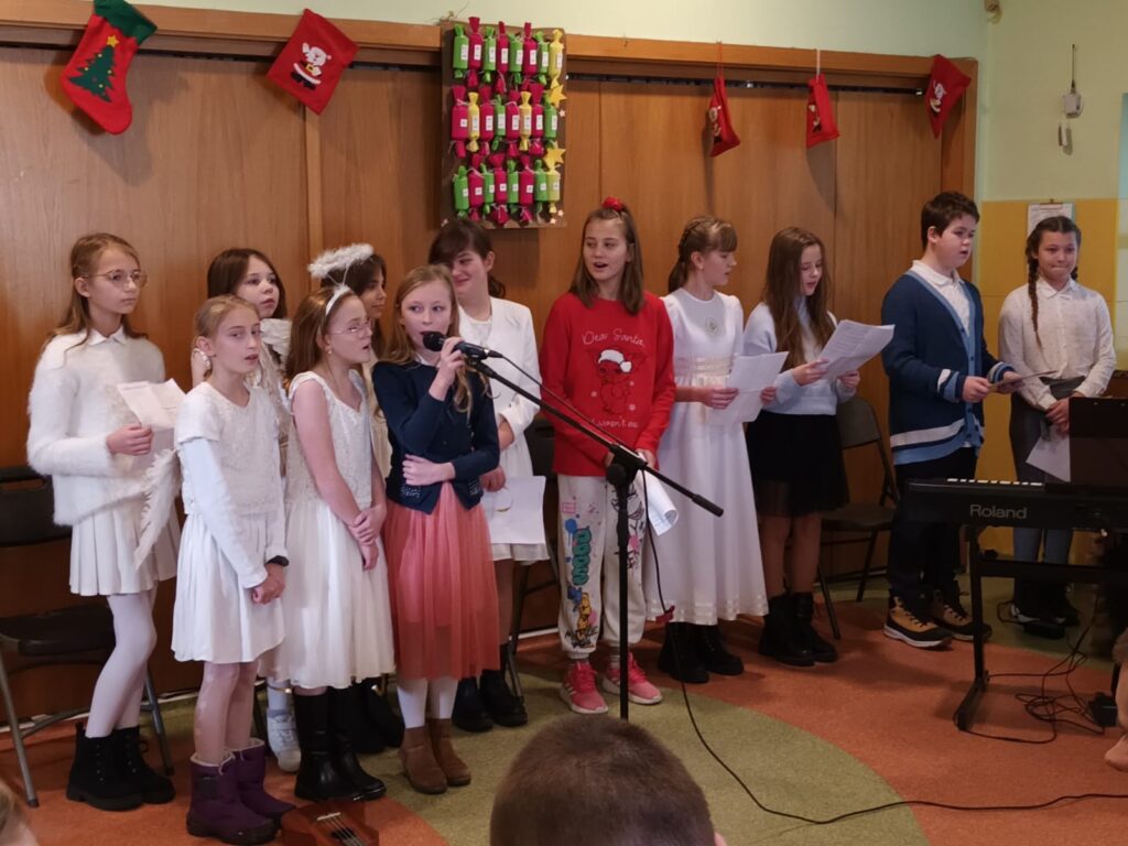 Grupa dzieci śpiewających do mikrofonów. 